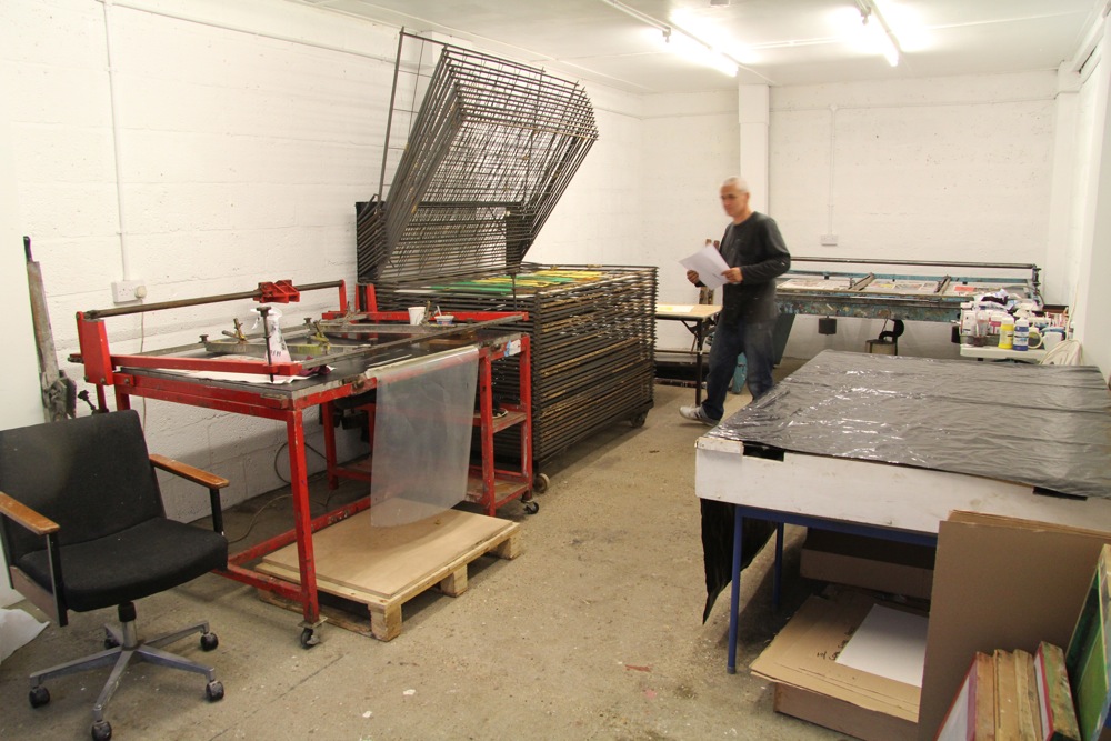 Screen printing studio with vacuum beds, drying racks and large exposure table.